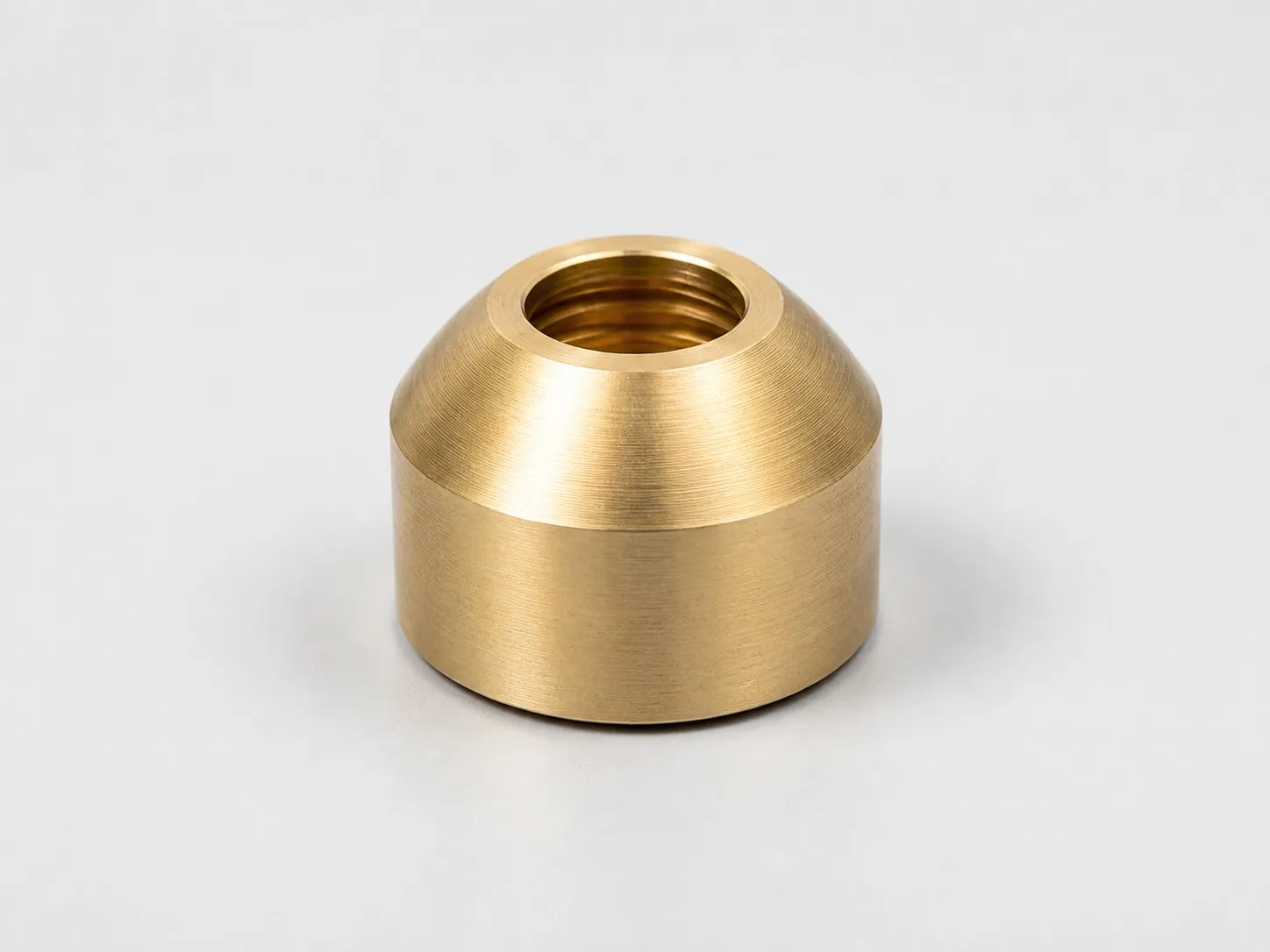Bucha de bronze usinada com furo central roscado e acabamento externo.